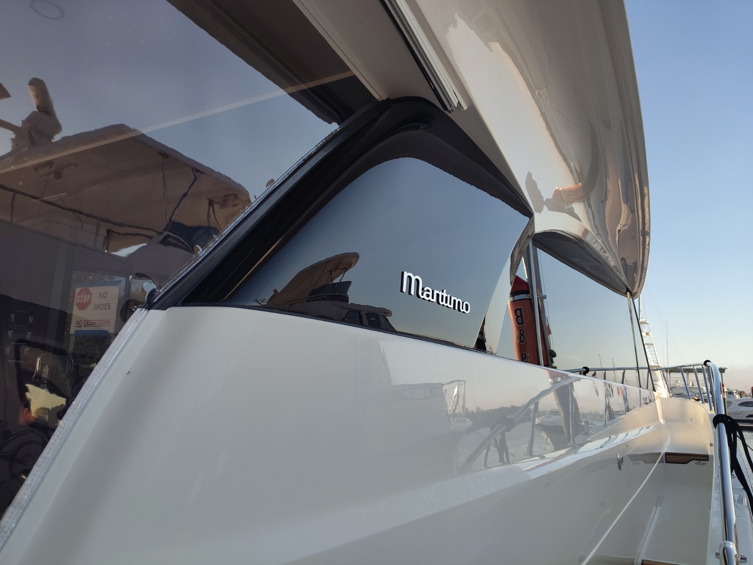 Close-up of a Maritimo yacht’s reflective glazing, white exterior and stainless rail